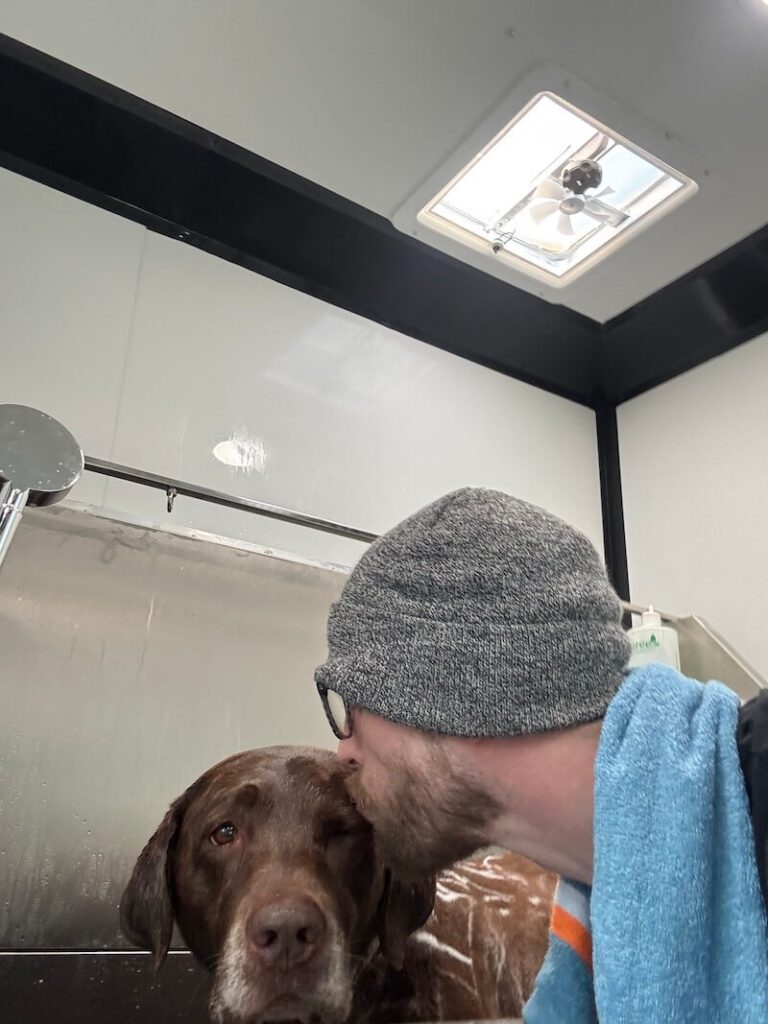Steven kissing a happy canine customer at The Groomin' Cowboy Mobile Saloon