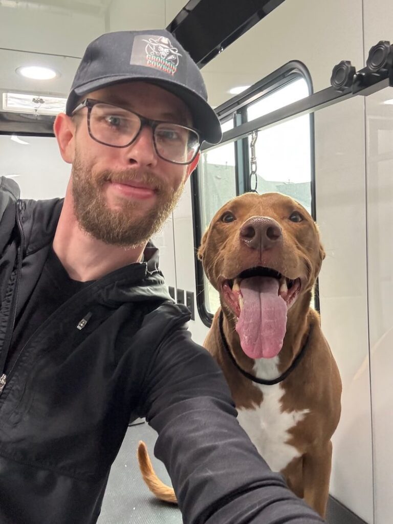 Steven posing with a happy canine customer at The Groomin' Cowboy Mobile Saloon