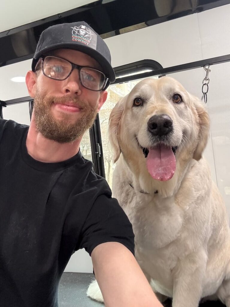 Steven smiling with a happy canine customer at The Groomin' Cowboy Mobile Saloon
