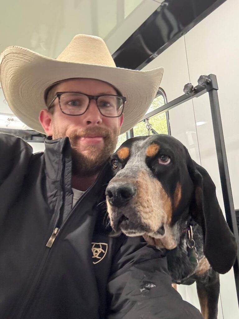 Steven wearing a cowboy hat and posing with a happy canine customer at The Groomin' Cowboy Mobile Saloon