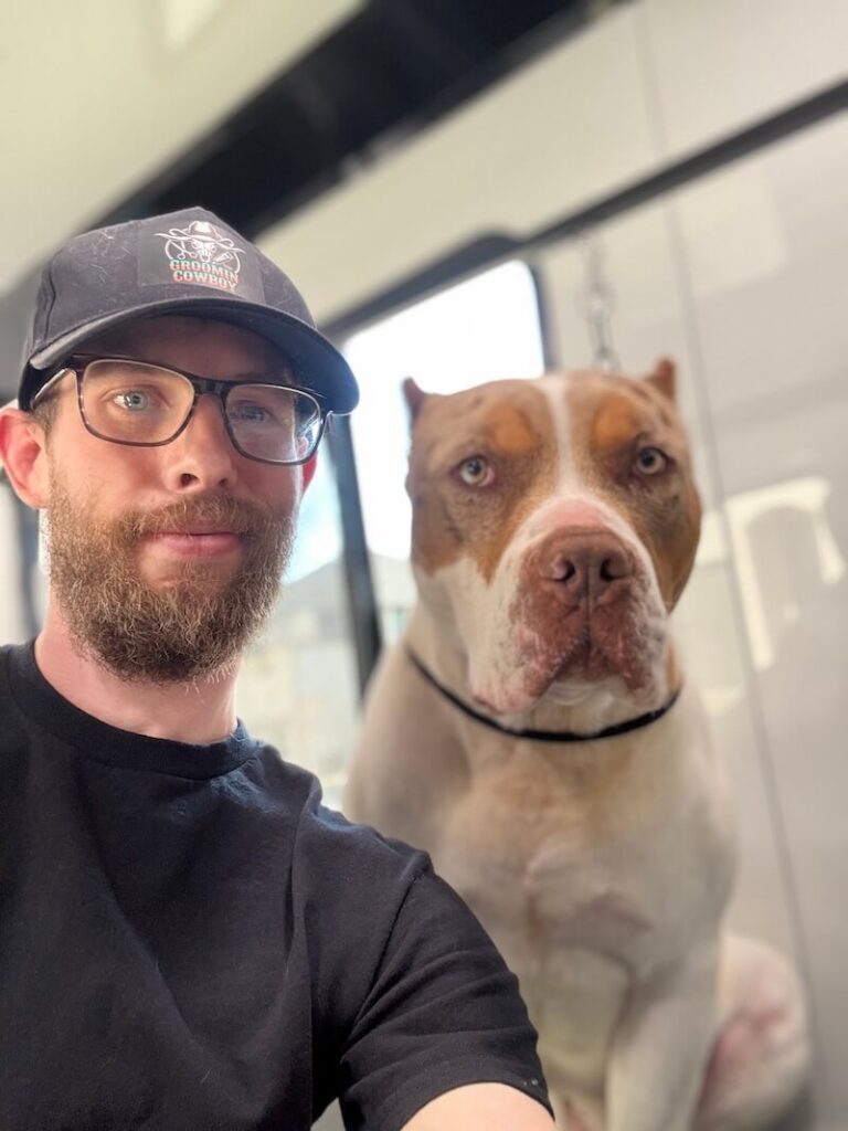 Steven posing with a happy canine customer at The Groomin' Cowboy Mobile Saloon