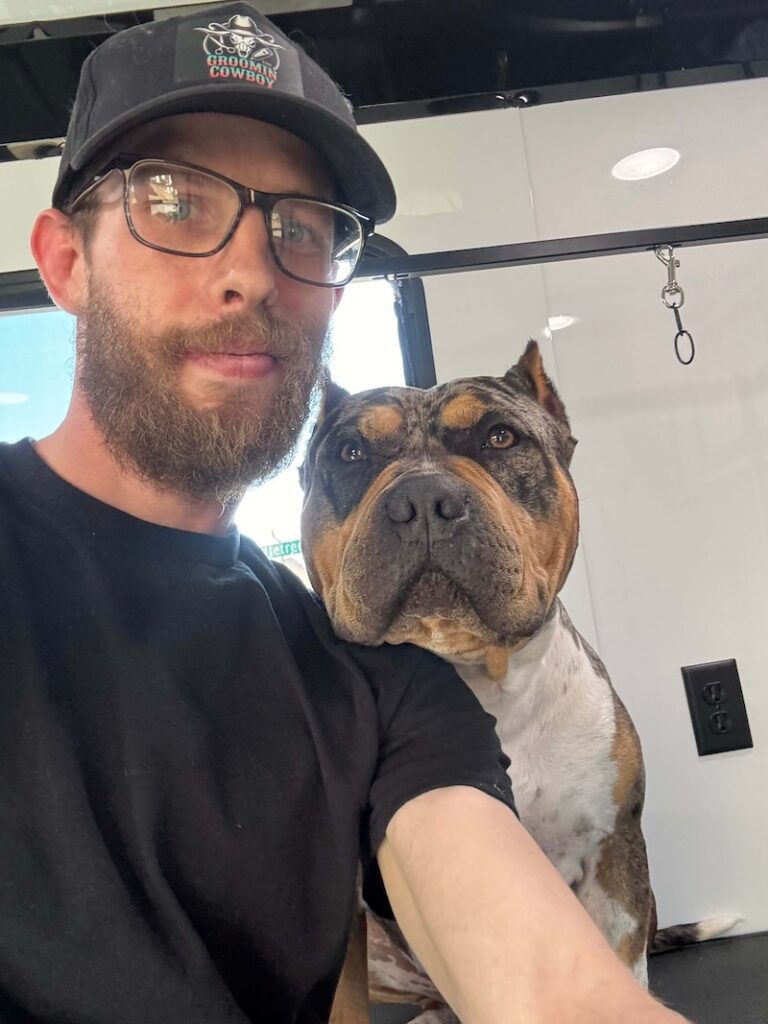 Steven posing with a happy canine customer at The Groomin' Cowboy Mobile Saloon